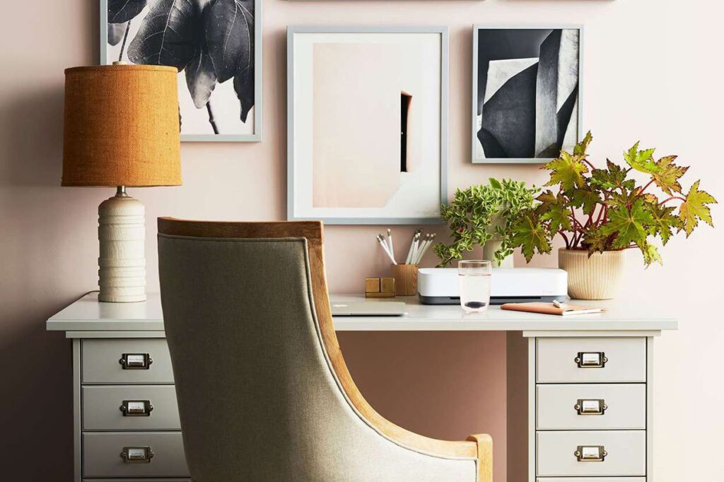 a home office setup with some greens on table a lamp and other essentials on table