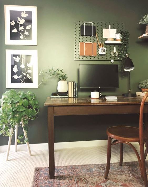 small home office setup with green walls and table chair and other essentials