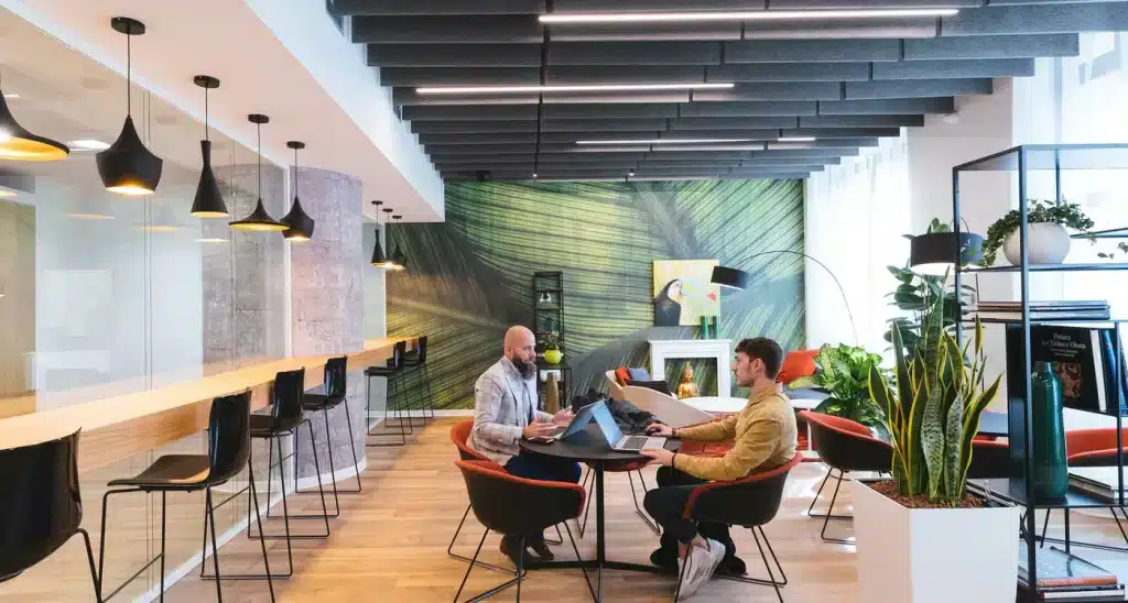 two person talking to eachother in a office sitting on the chair with lapotop and papers in hands