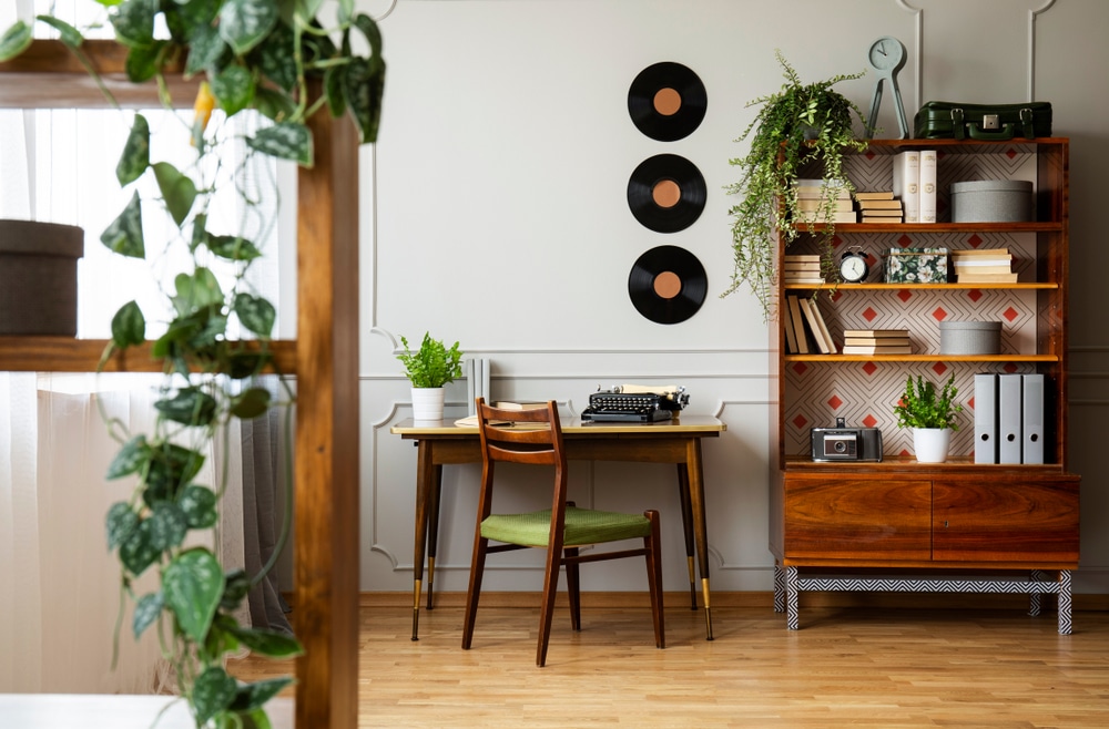 Black retro typewriter on a unique wooden desk a mid century modern chair and a renovated bookcase in a hipster home office interior