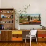 a room with a hoem office setup along with table chair a rack and wall painting