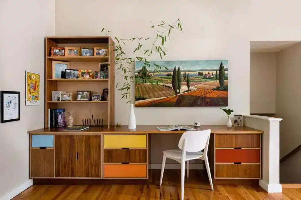 a room with a hoem office setup along with table chair a rack and wall painting