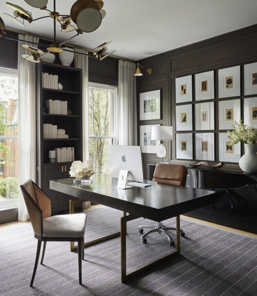 large windows in a black home office art pieces on wall a system a wokring desk and chairs