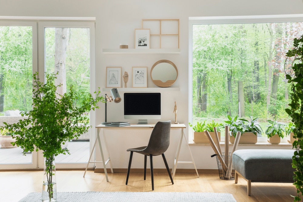 a home office with a chair industrial style white table greenery art work displayed on shelves