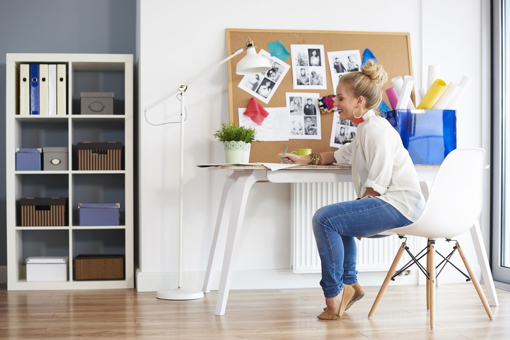 a woman sitting on white chair working on something a vision board with photographs