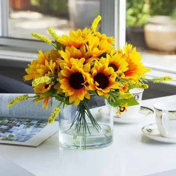 sunflowers in a vase on a table blurred view of cups