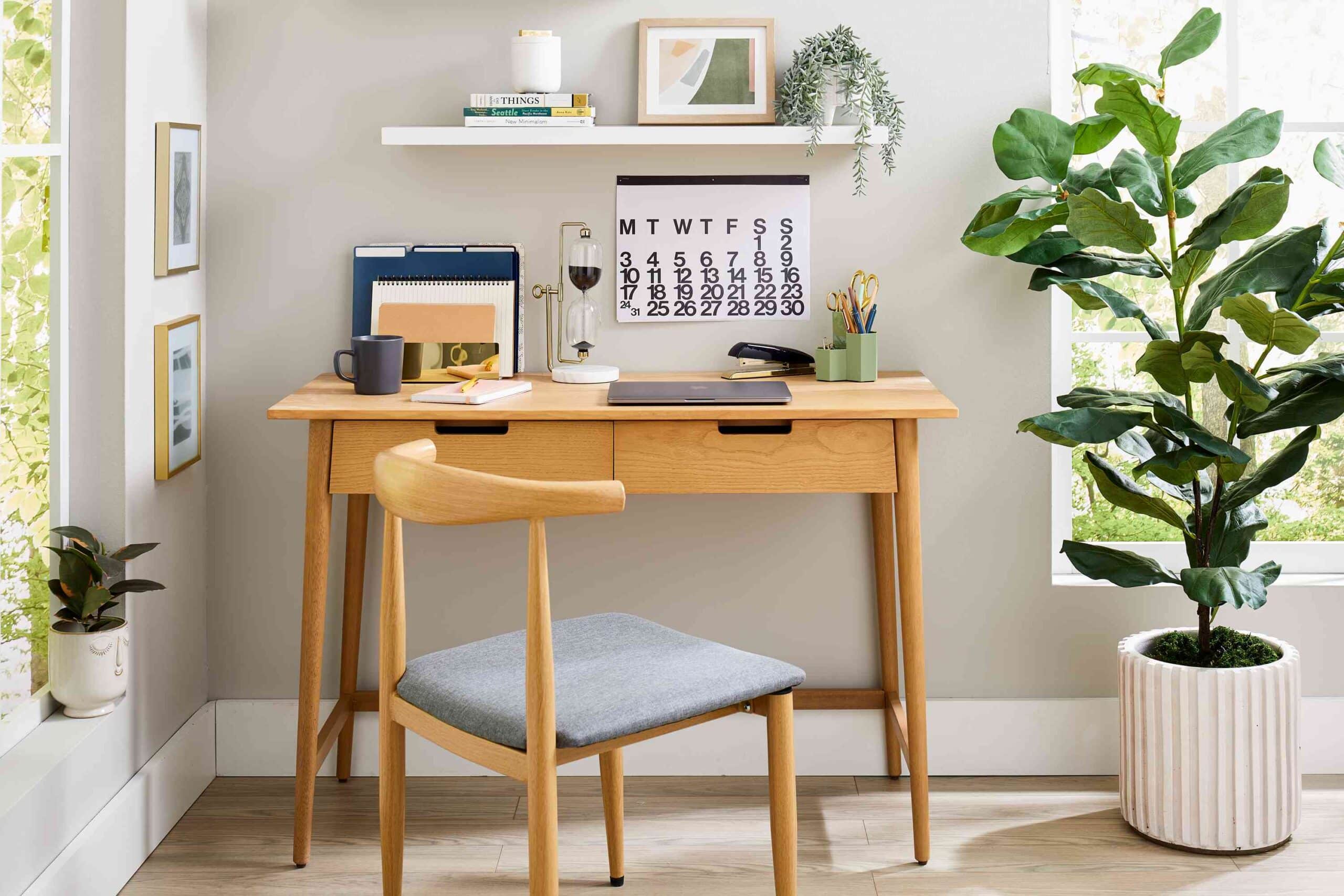 wooden desk a chair a pot books on floating shelves a laptop