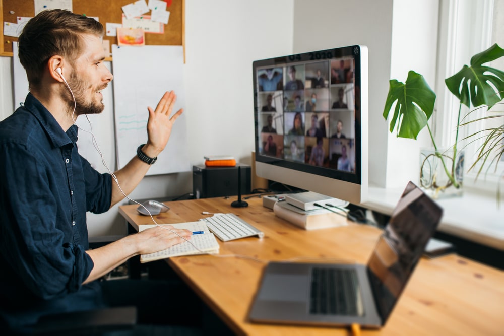 Business video conferencing. Young man having video call via computer in the home office.