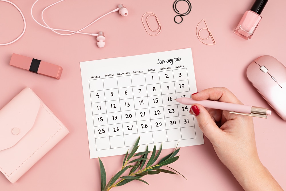 Desktop with calendar for january and office supplies in pink color