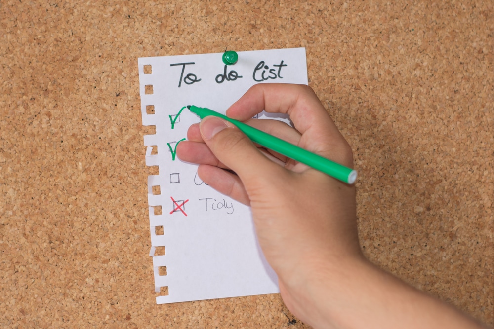 Hand Checking A Box Of A Checklist To Do List with cork background
