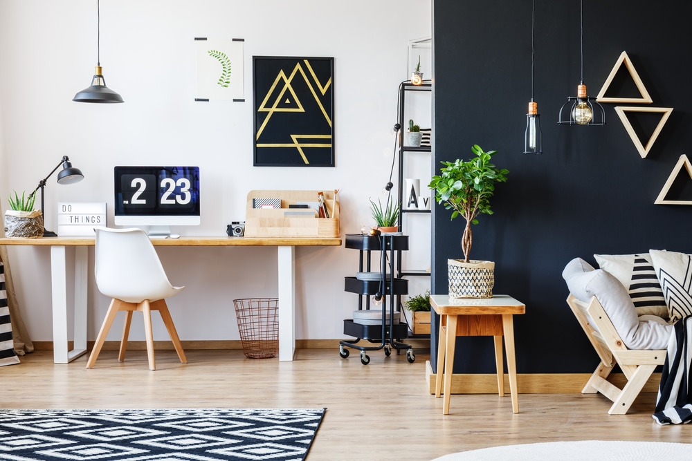 Nordic natural interior in stylish open studio for a freelancer with sofa, black wall and office space with desk and black accent