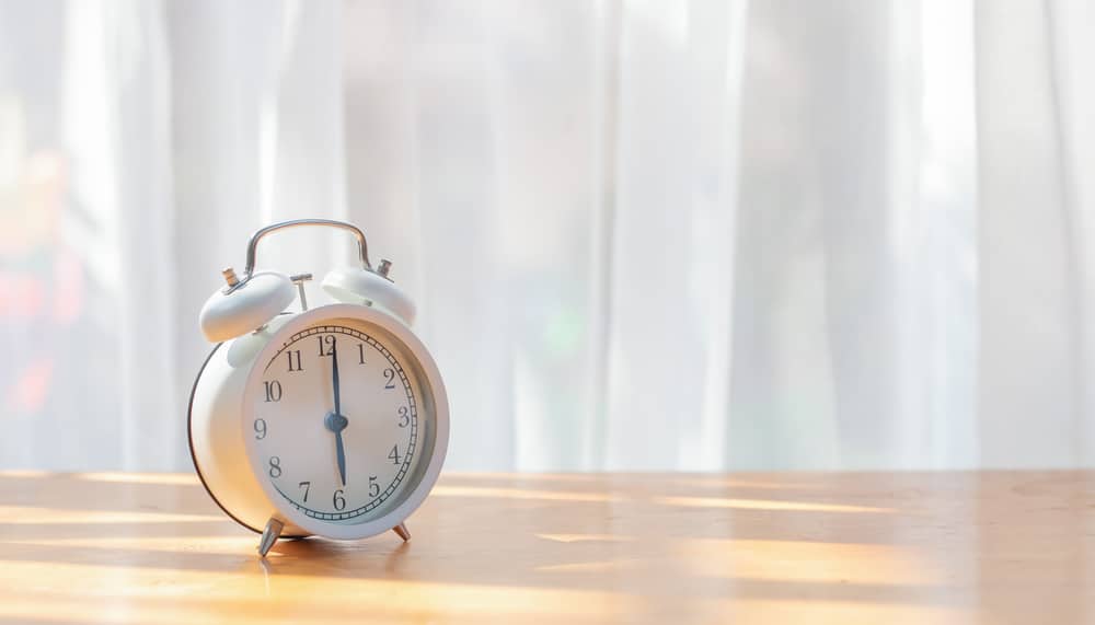 White Alarm Clock On Desk With Beautiful Curtain For Background